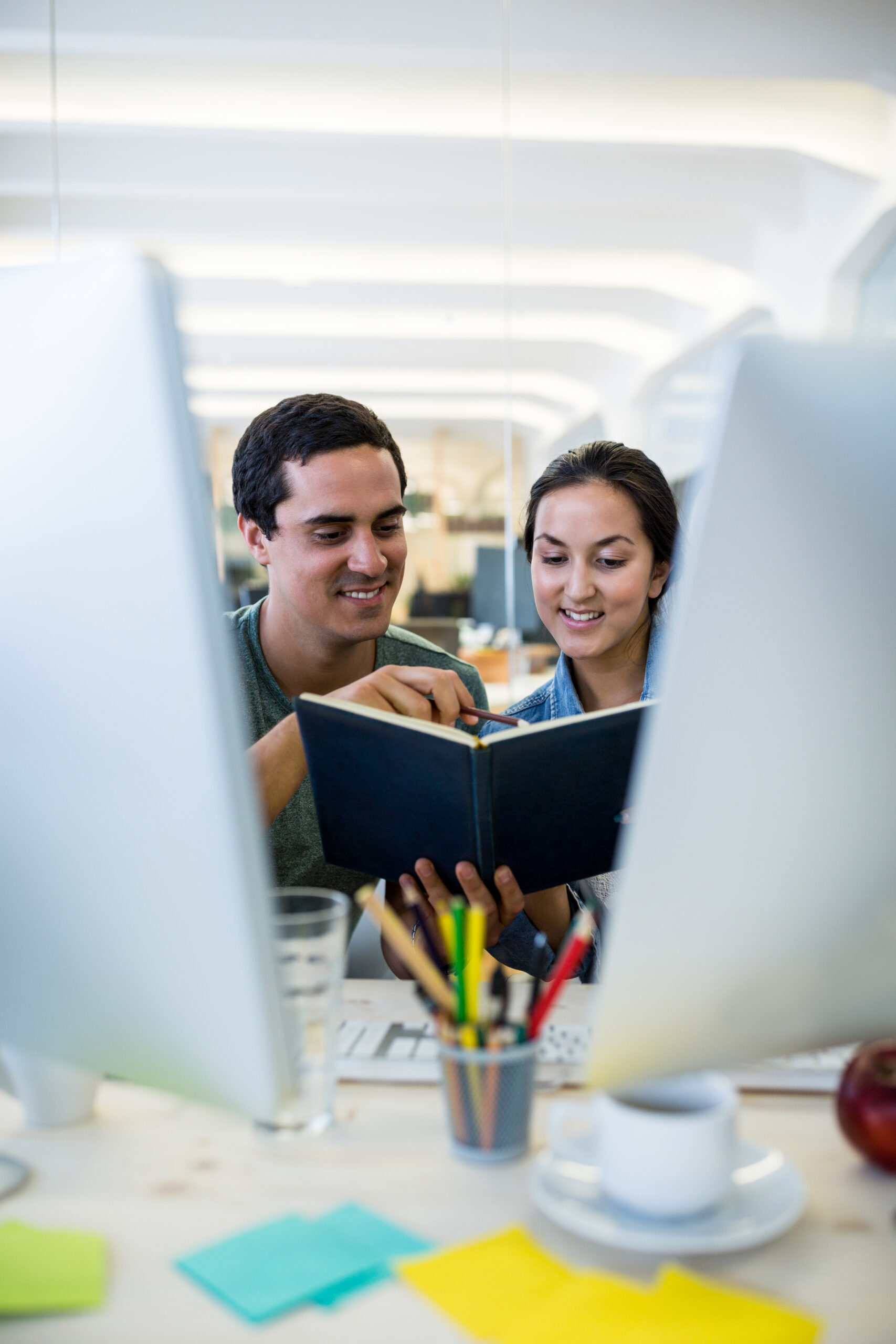 Male and female graphic designers interacting over a diary in office